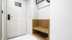 A closed door with a metal handle, a wooden shelf unit with a red box, and a white wall with a black horizontal line.