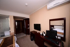 A hotel room with a bed, a desk with a computer, a television, and an air conditioning unit. - Jixi City Guesthouse (Jixi)