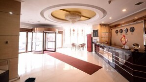 A hotel lobby with a reception desk, a chandelier, a red carpet, and a wall with clocks. - Jixi City Guesthouse (Jixi)