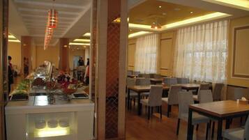 A hotel dining area with a buffet, multiple tables, and chairs.