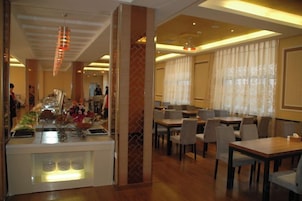 Comedor de hotel con barra libre, varias mesas y sillas.