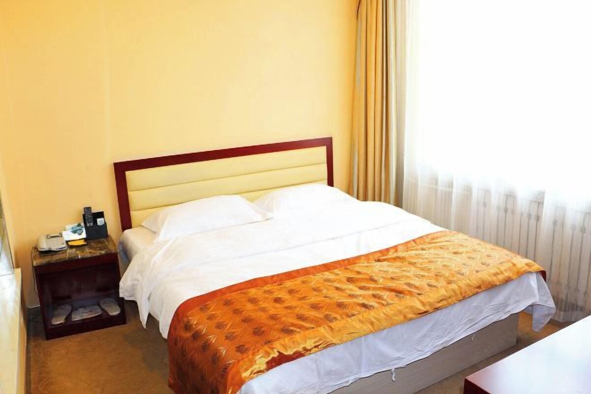 Une chambre d’hôtel avec un lit, une table de chevet et une fenêtre avec des rideaux.