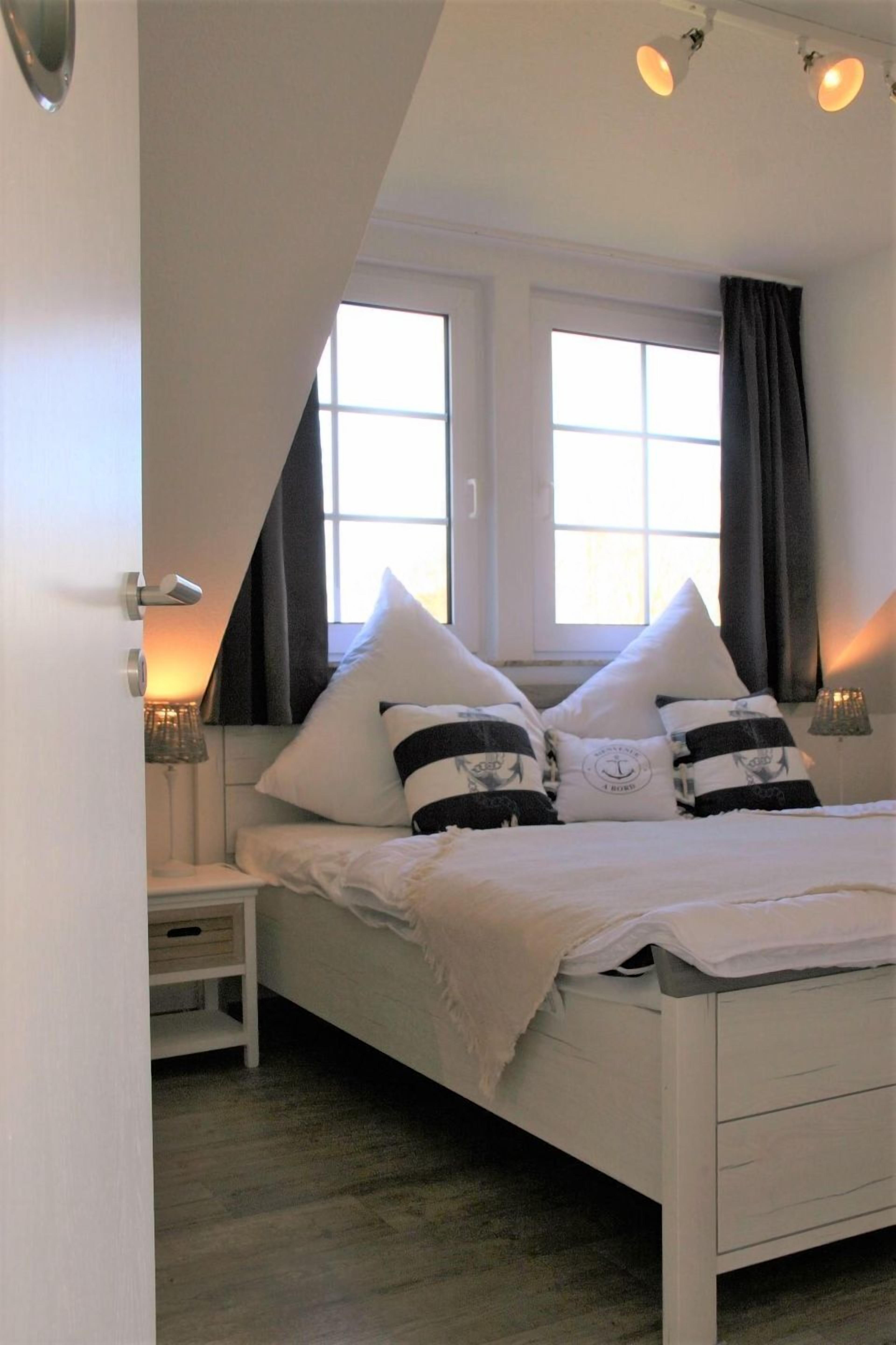 Ein Schlafzimmer mit Bett, Nachttischen und einem Fenster mit Vorhängen.