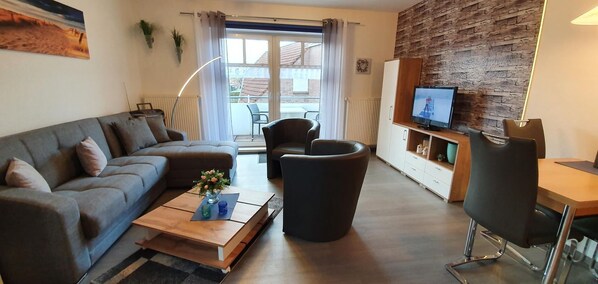 A modern living room with a sofa, coffee table, and a TV on a wooden cabinet.