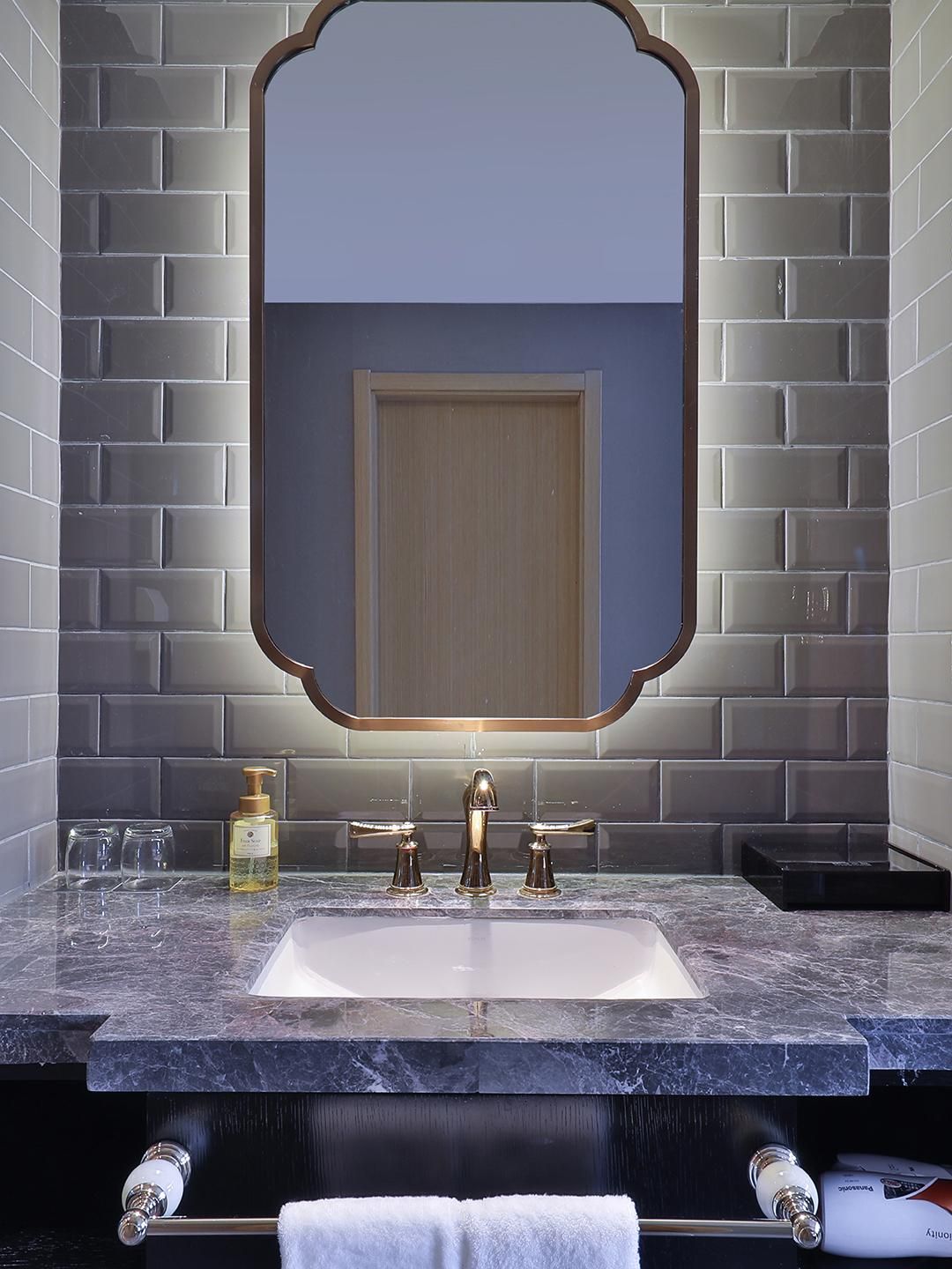Un bagno con un lavabo in marmo, uno specchio grande e un porta asciugamani.