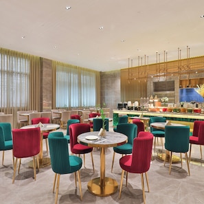 A modern restaurant with round tables and vibrant chairs, a bar area, and large windows with curtains. - Crystal Orange Hotel Kunming Dongfenglu Henglong S (Kunming)