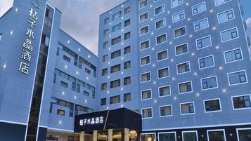 A modern hotel building with multiple floors, a prominent entrance with steps, and illuminated windows.