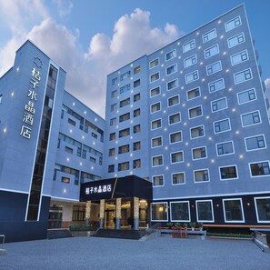 Ein modernes Hotelgebäude mit mehreren Etagen, einem markanten Eingang mit Stufen und beleuchteten Fenstern.