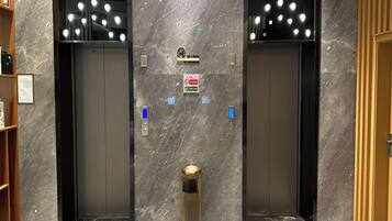 A modern elevator with a marble wall and a trash can in the center.