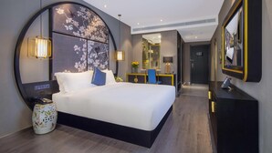 Een moderne hotelkamer met een groot bed, nachtkastje en een spiegel.