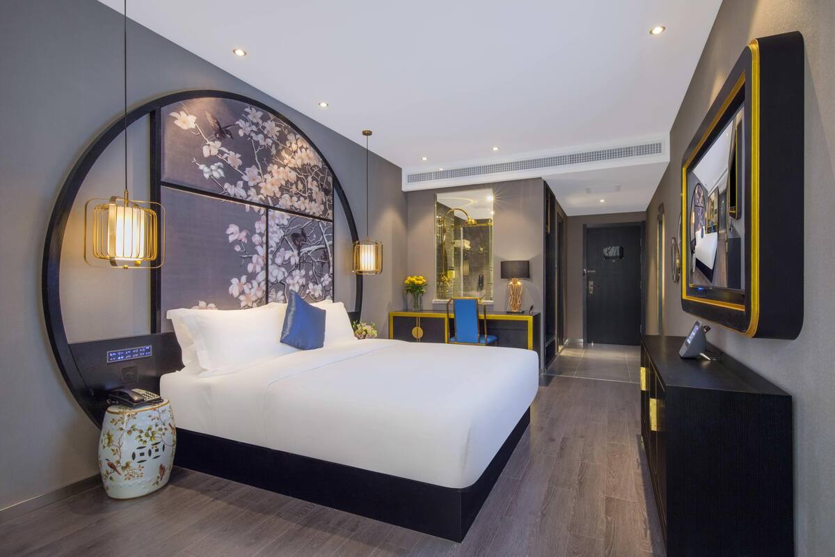Una habitación de hotel moderna con una cama grande, mesitas de noche y un espejo.