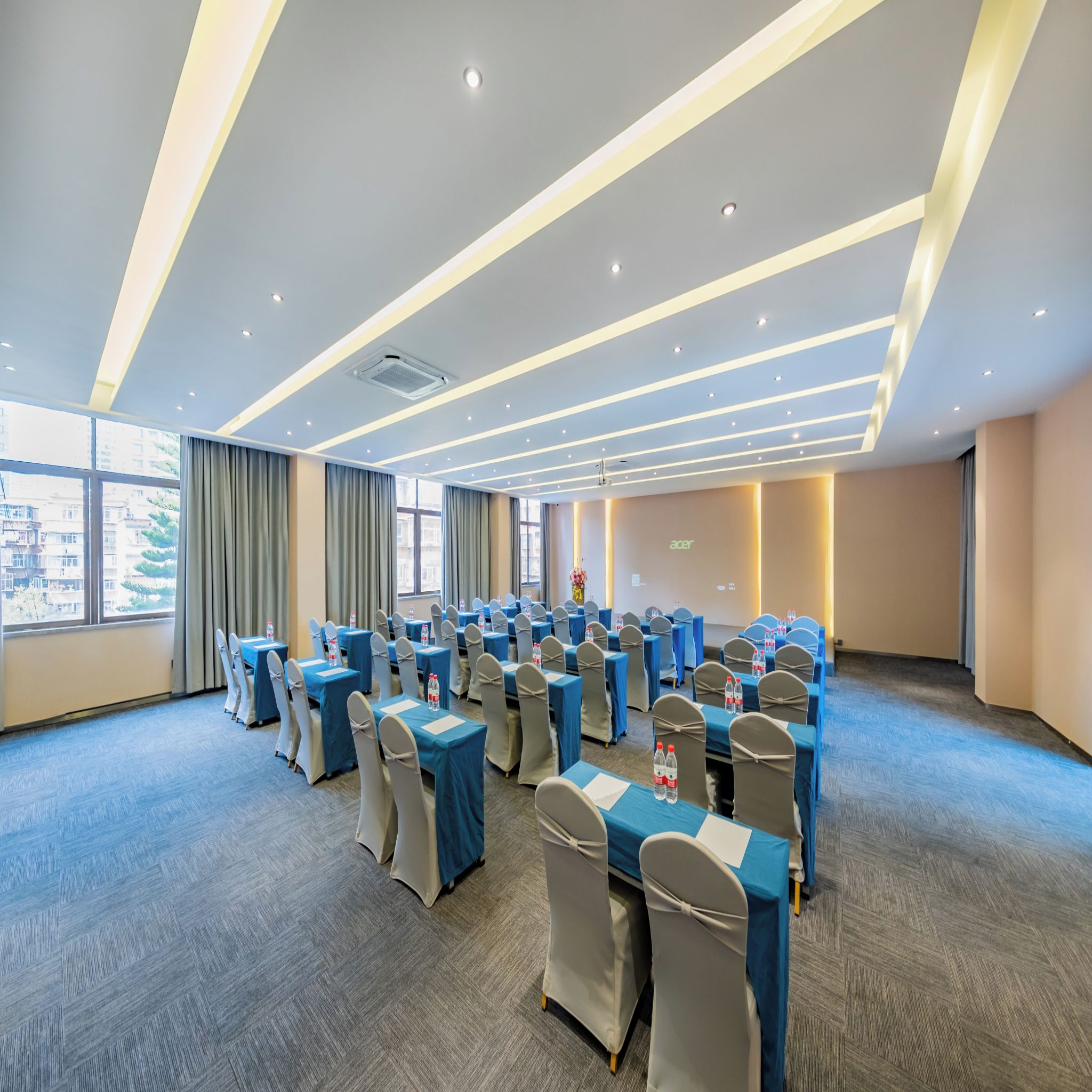 A conference room with tables and chairs, large windows, and a modern ceiling design.