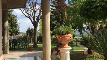 Un'area esterna riparata con una struttura a pergola, piante in vaso e vista sul paesaggio circostante.