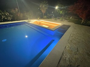 Ein Pool mit einer eingelassenen Sitzecke und einer Steinsäule.
