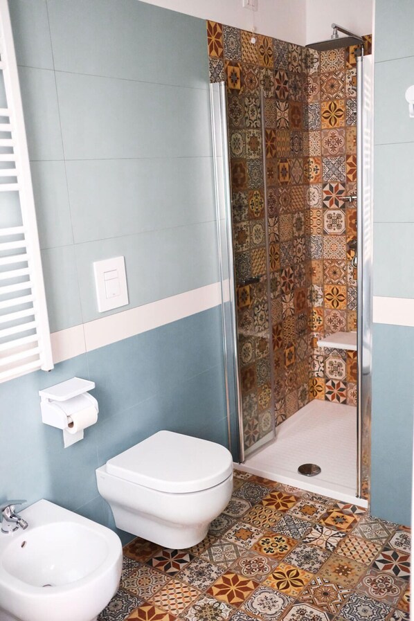 A bathroom with a shower, toilet, and bidet.
