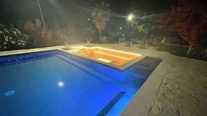 Una piscina con una zona de estar hundida y un muro de piedra.