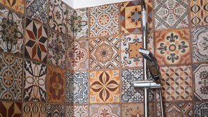Una ducha de diseño moderno frente a una pared de baldosas con un intrincado patrón.
