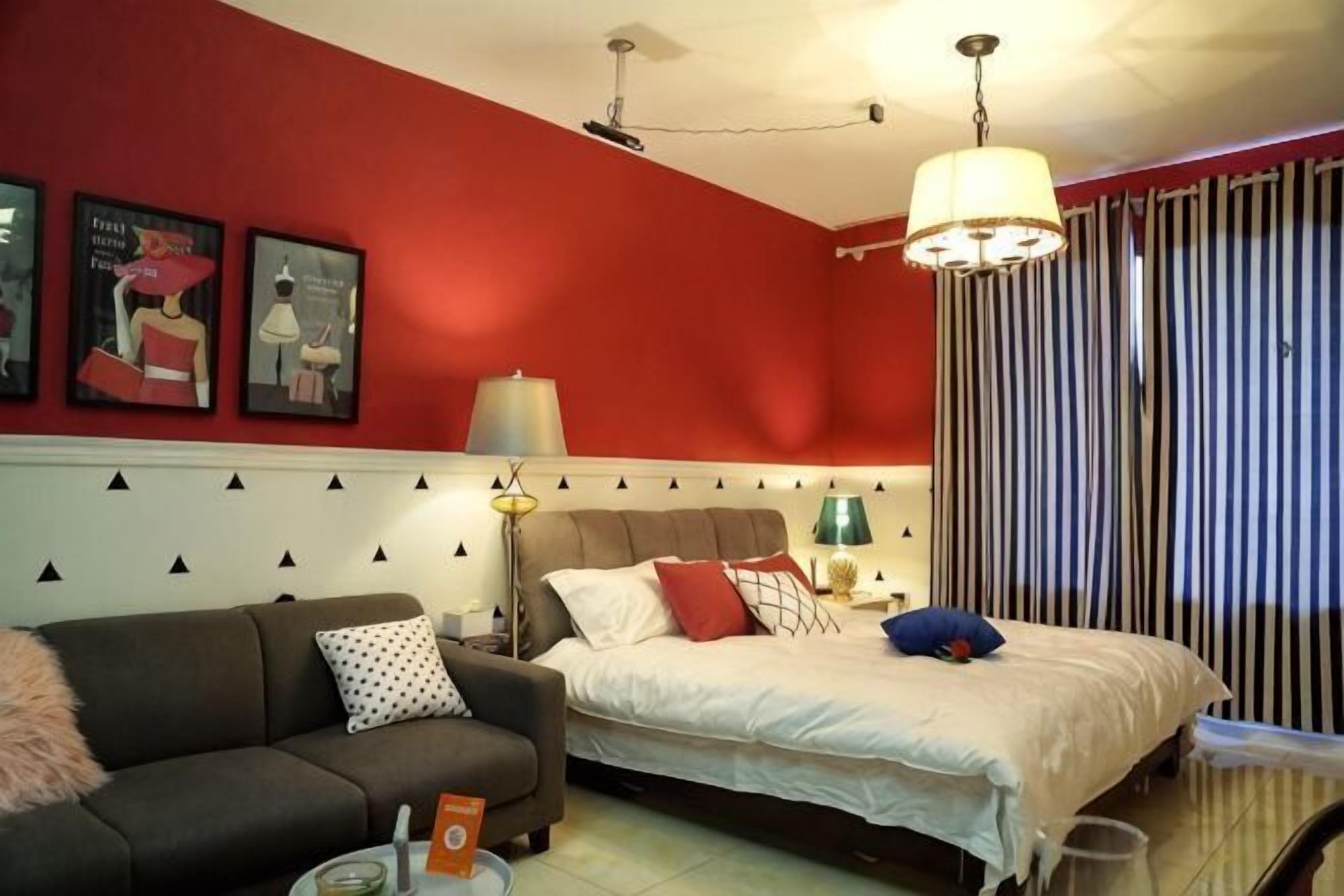 A bedroom with a bed, a sofa, a lamp, and a window with curtains.