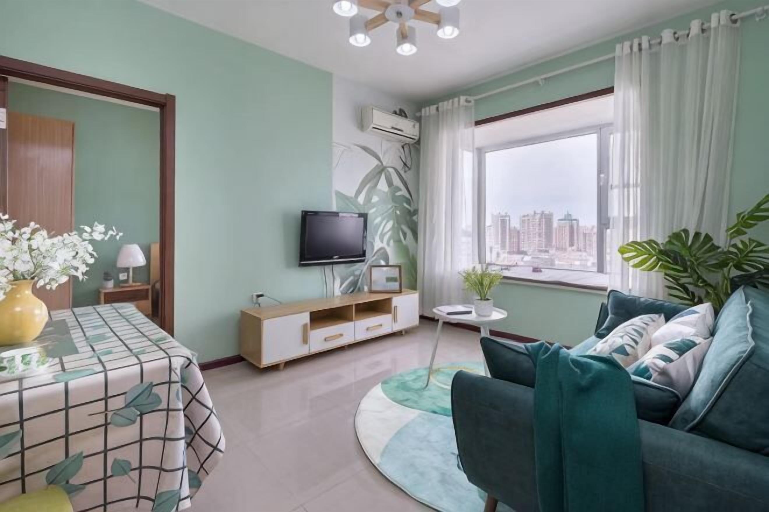 A living room with a sofa, a TV, a dining table with a patterned tablecloth, and a window with a city view.