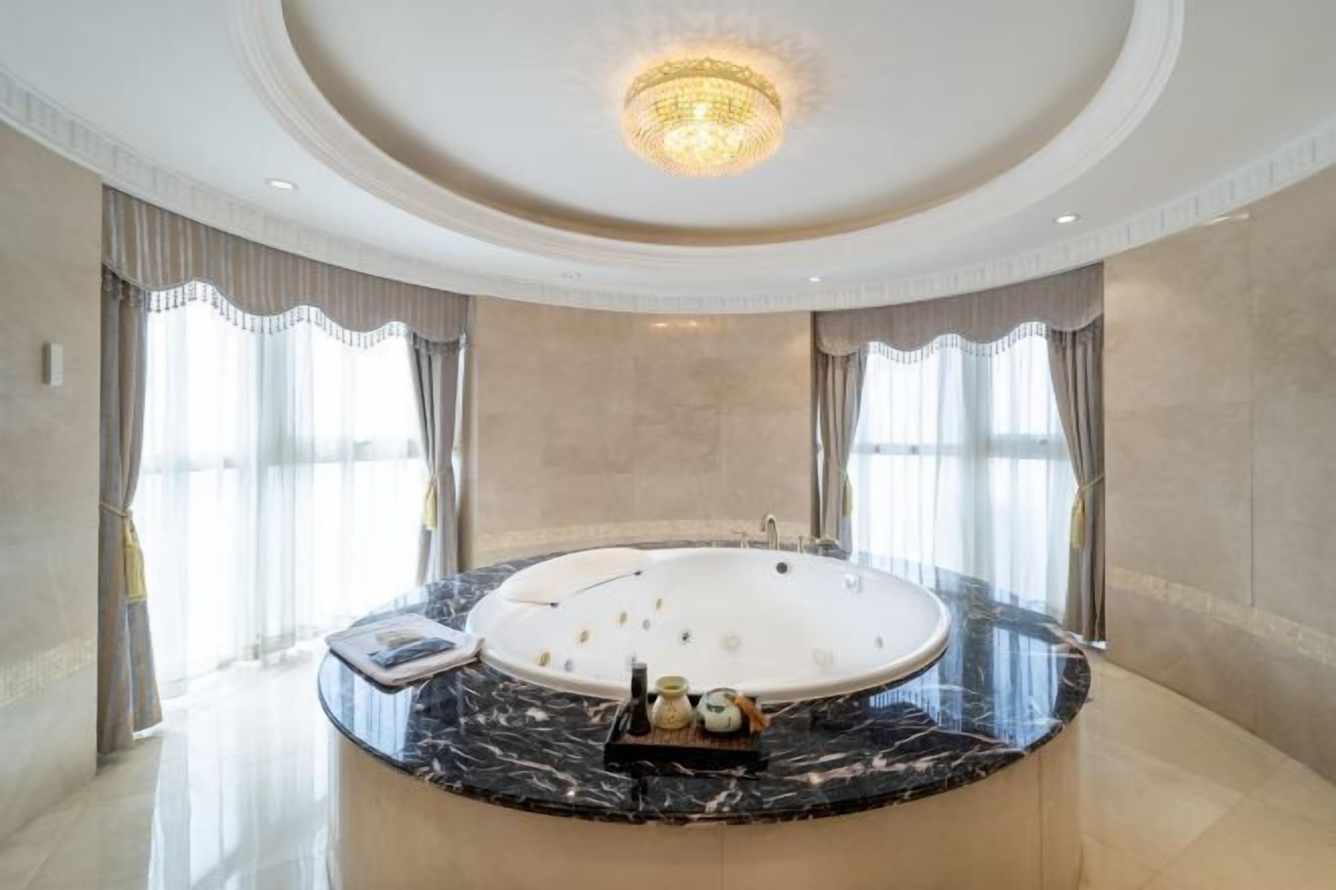 Une salle de bain luxueuse avec une grande baignoire ovale, un comptoir en marbre et un lustre.