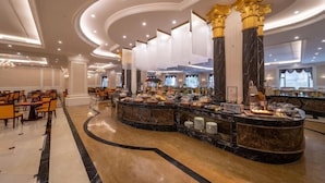 A spacious lobby with a marble reception desk, golden columns, and a seating area with chairs. - Howard Johnson Junhe Hotel Beijing (Beijing)