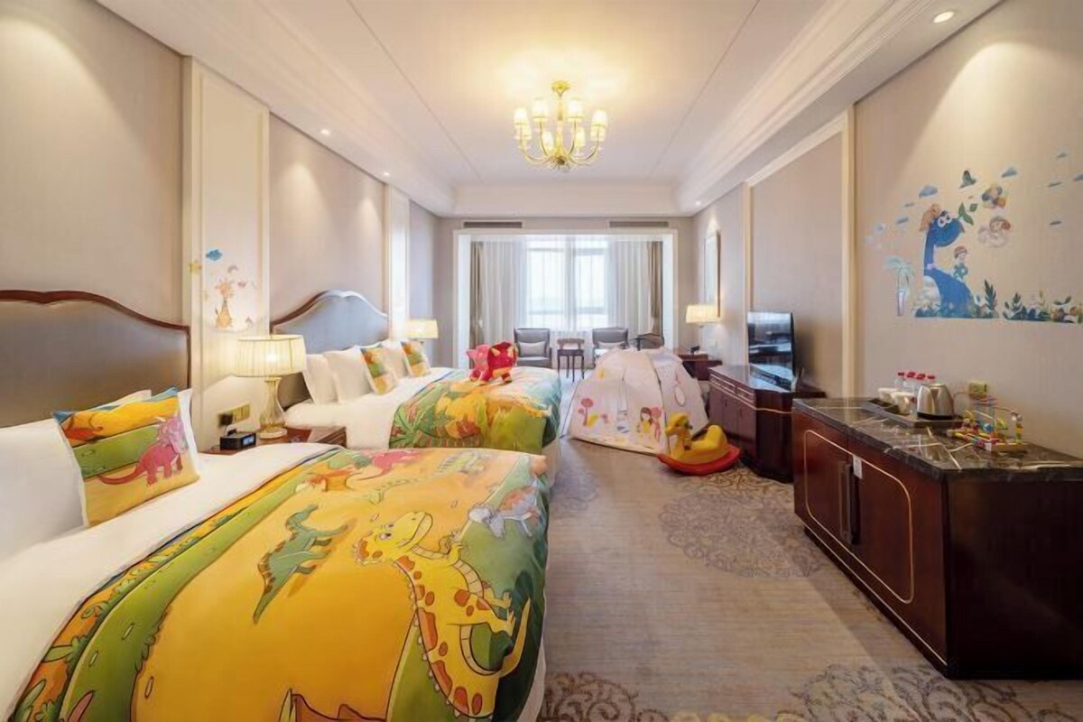 Une chambre d’hôtel avec deux lits, un bureau, une télévision et un lustre.