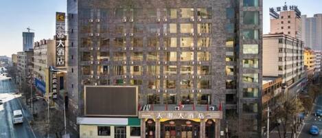 A multi-story hotel with a prominent entrance, several parking spaces, and a clear view of the street.