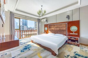 A hotel room with a large bed, a desk, a chair, a nightstand, a lamp, a clock, and a view of the city. - Tianyuan Hotel (Yongdeng)