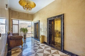 A hotel lobby with a checkered floor, a sofa, a chandelier, and a large mirror. - Tianyuan Hotel (Yongdeng)