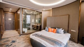 A modern hotel room with a large bed, a walk-in closet, a bathroom with a glass shower, and a large mirror. - Villa Lido (Laiyang)