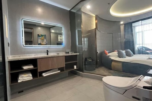 A modern hotel room with a large mirror, a shower area, a bed with pillows, and a toilet. - Villa Lido (Laiyang)
