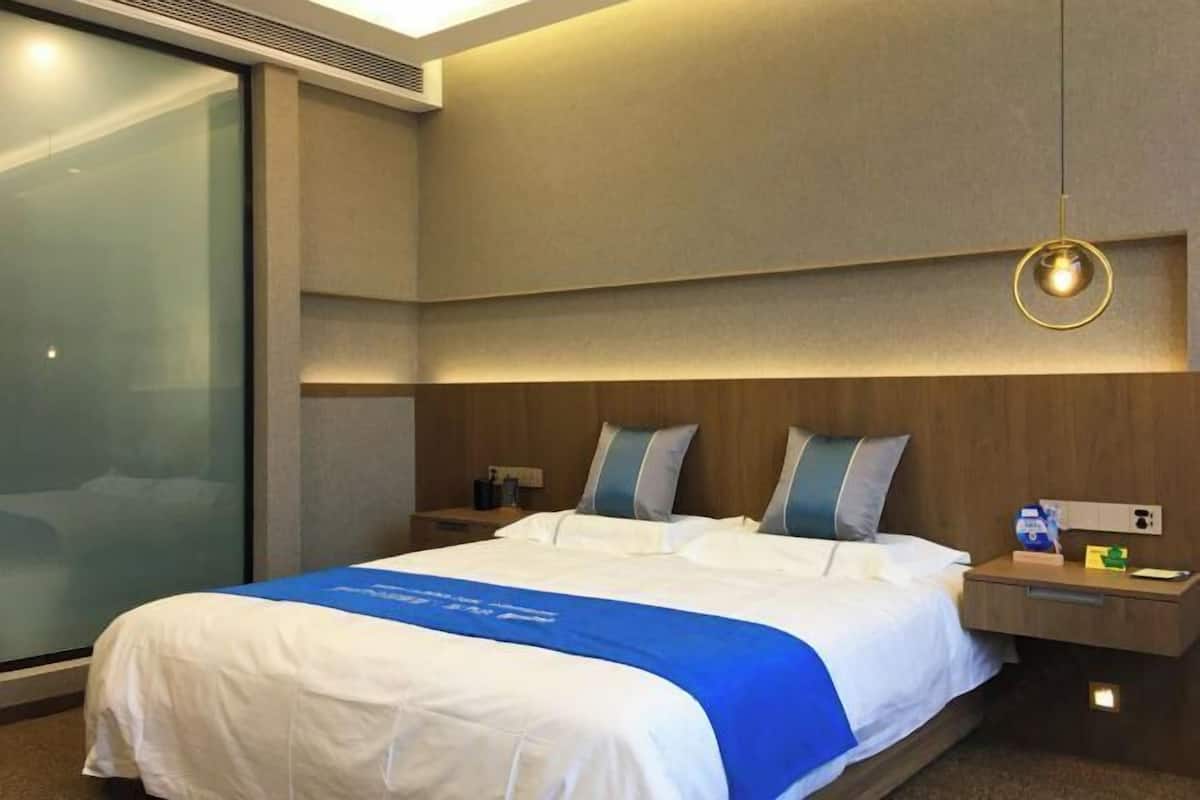 Habitación de hotel con una cama grande, una mesita de noche y un aire acondicionado instalado en la pared.