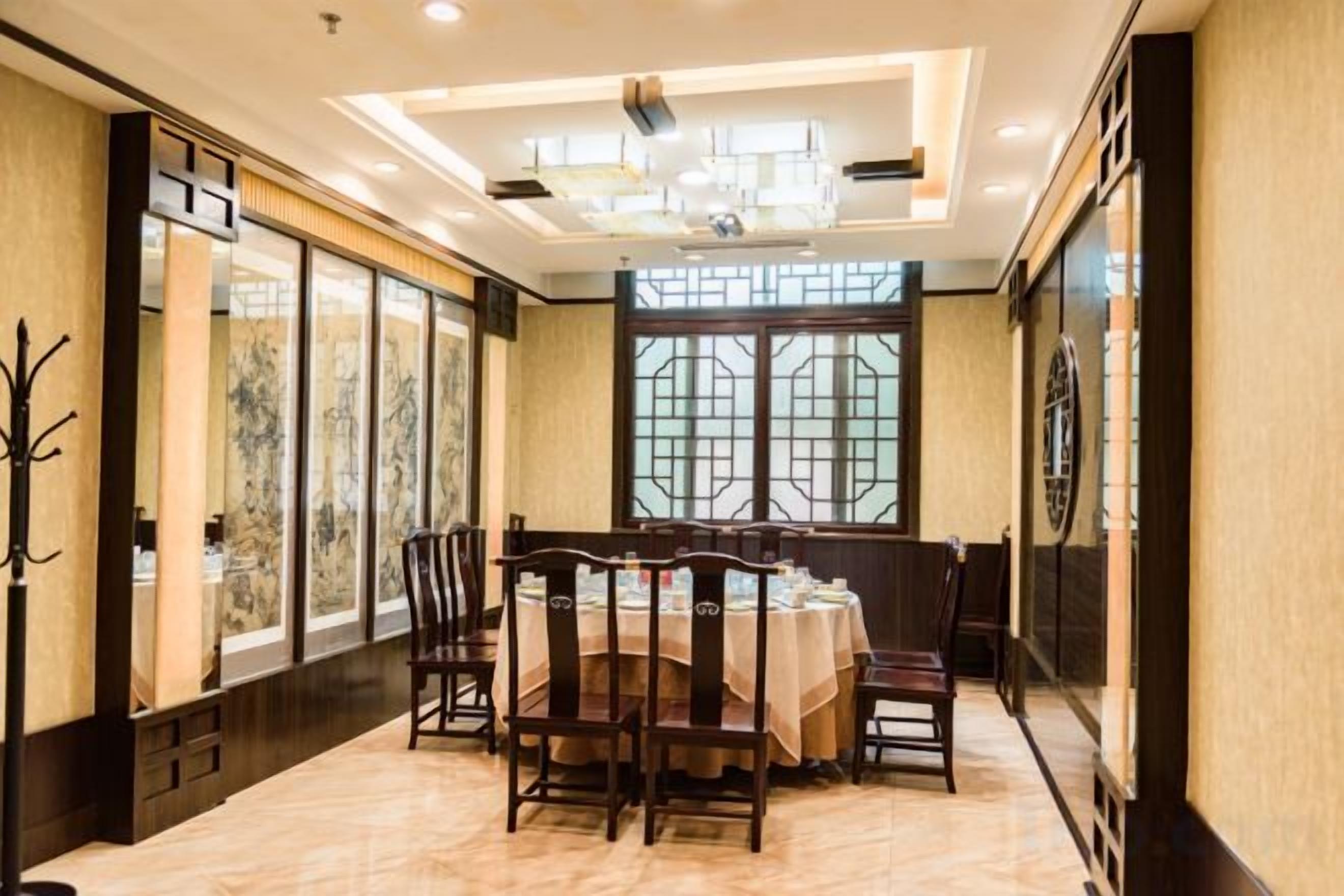 A dining area with a round table, chairs, and a chandelier.