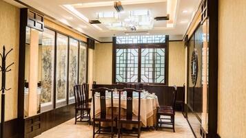 A dining area with a round table, chairs, and a chandelier.