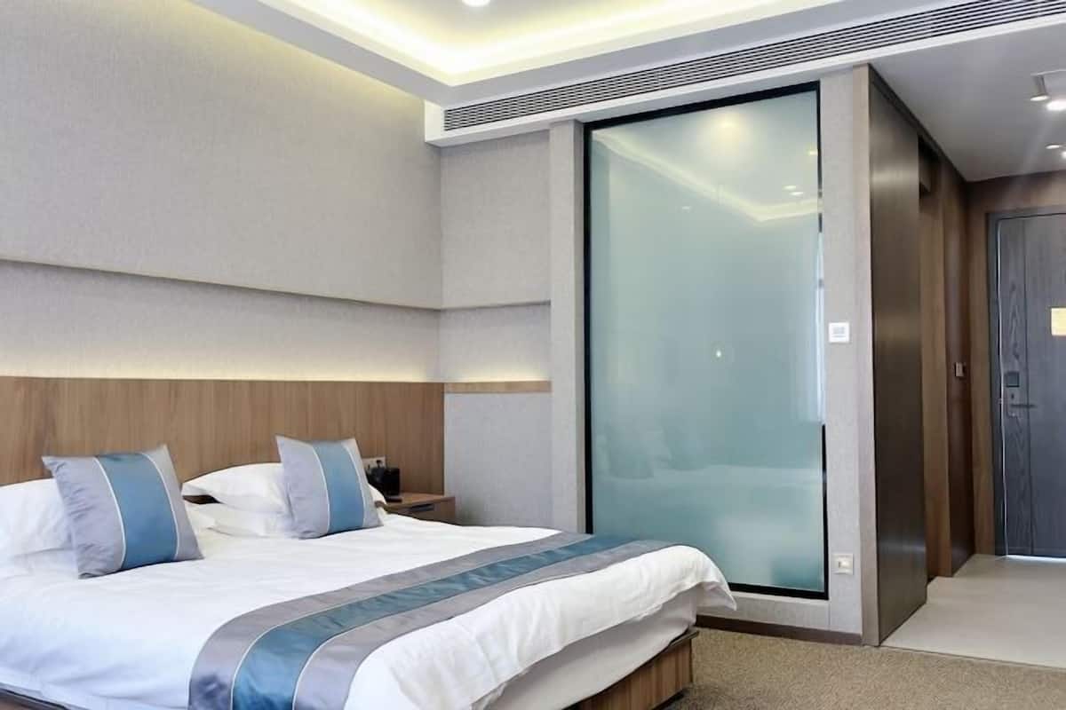 Una habitación de hotel moderna con una cama grande, un armario con puerta corredera y una mesita de noche con lámpara.