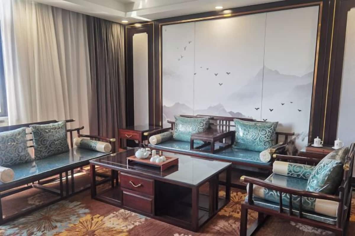 Un salón de estilo tradicional con un conjunto de sofás, una mesa de centro y una pared decorativa con un paisaje montañoso.