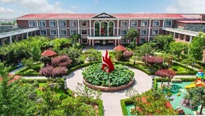 A large building with a central courtyard, surrounded by lush greenery and a distinctive red sculpture. - Villa Lido (Laiyang)
