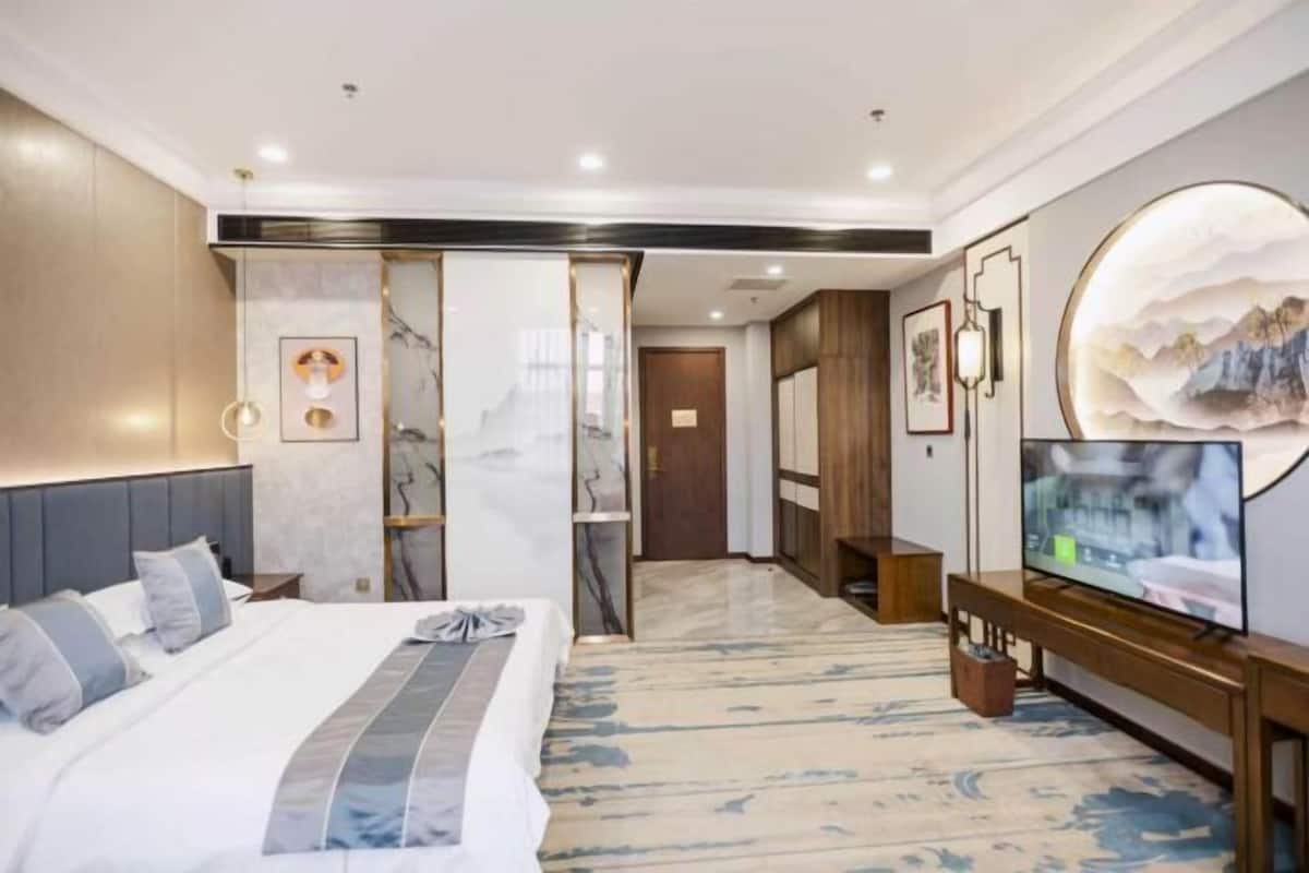 Habitación de hotel con cama, televisión y una obra de arte grande en la pared.