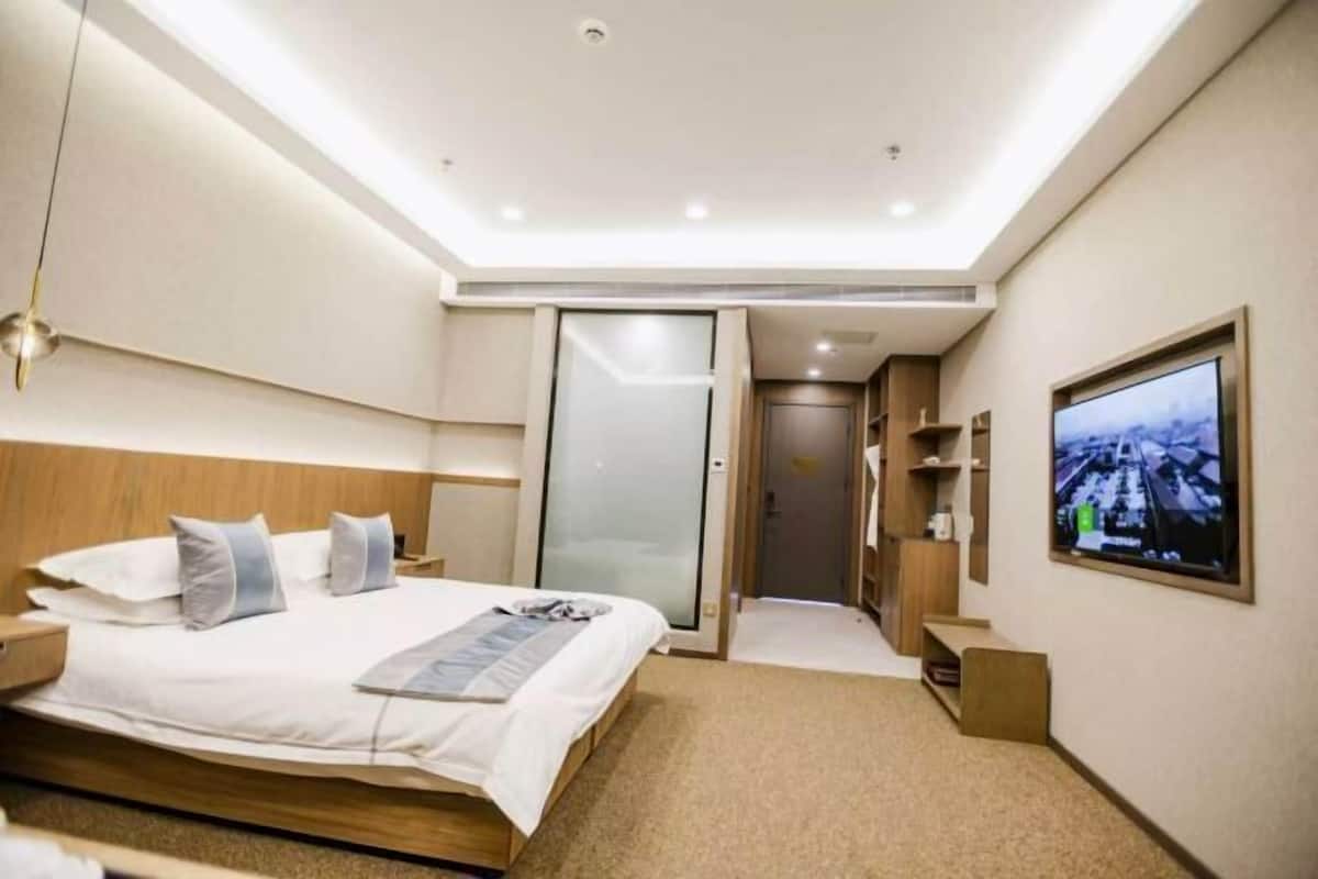 Habitación de hotel con cama, televisor, puerta corredera y un escritorio pequeño.