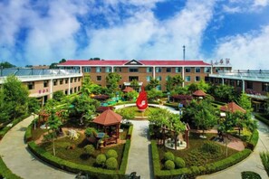 A courtyard with a central red sculpture, surrounded by buildings with red roofs and multiple floors. - Villa Lido (Laiyang)