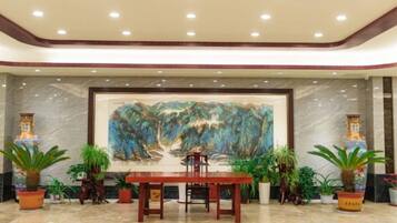 A lobby with a marble floor, a wooden reception desk, and a large abstract painting on the wall.