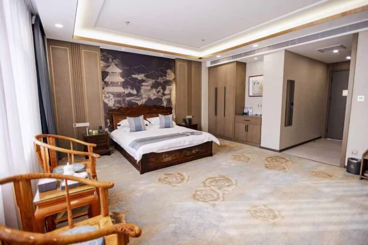 Una habitación de hotel con cama, muebles de madera, un muro decorativo y suelo alfombrado.
