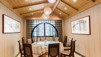 Un salón de conferencias con una mesa redonda, sillas de madera y obras de arte enmarcadas en las paredes.