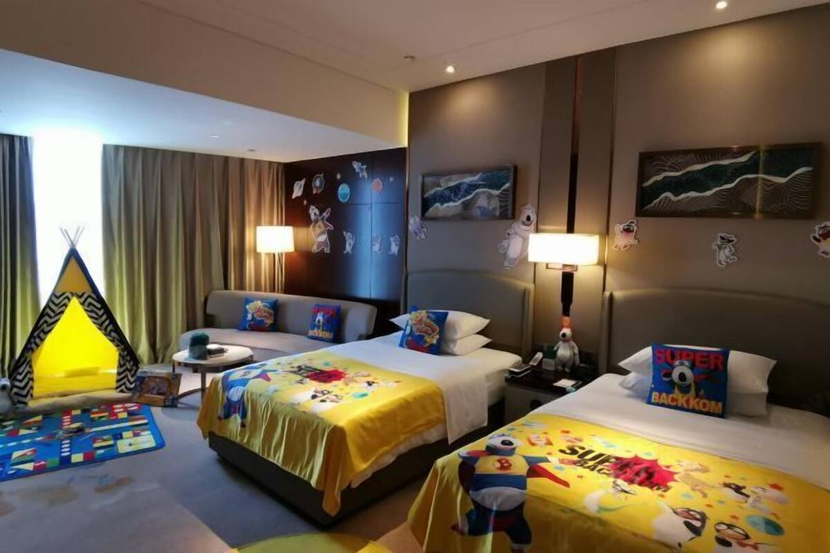 A hotel room with two beds, a sofa, a small table, and a tent-like structure.