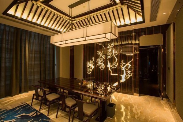A modern dining area with a glass-top table, chairs, and a decorative light fixture. - Phoenix Hotel (Wenshan City)
