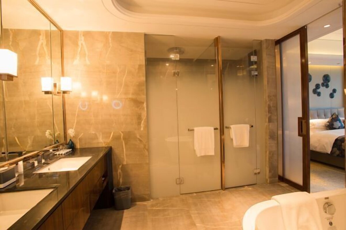 A modern bathroom with a large mirror, a bathtub, and a shower area.
