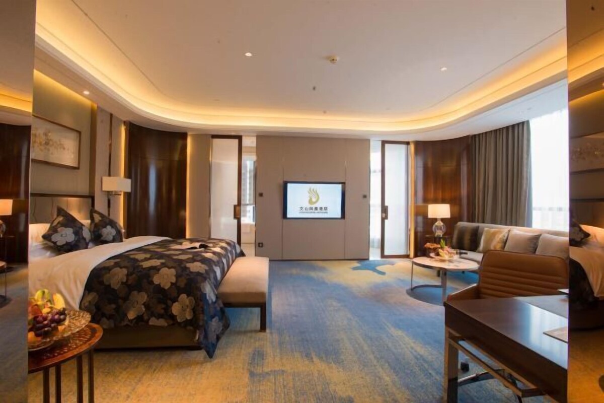 A hotel room with a bed, a sofa, a small table, and a TV.