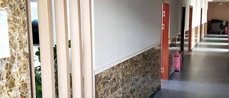 A hallway with a marble wall, a wooden slat partition, and a red door.