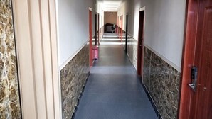 A hotel corridor with marble walls, red doors, and a blue carpet. - Wanluoyuan Theme Hotel (Antu)
