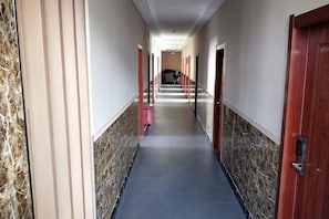 A hotel corridor with marble walls, red doors, and a blue carpet. - Wanluoyuan Theme Hotel (Antu)